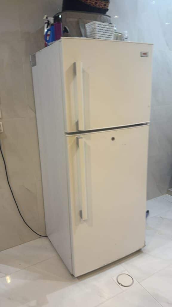 فني صيانة محترف يقوم بفحص وتصليح أعطال ثلاجة منزلية حديثة بسرعة فائقة